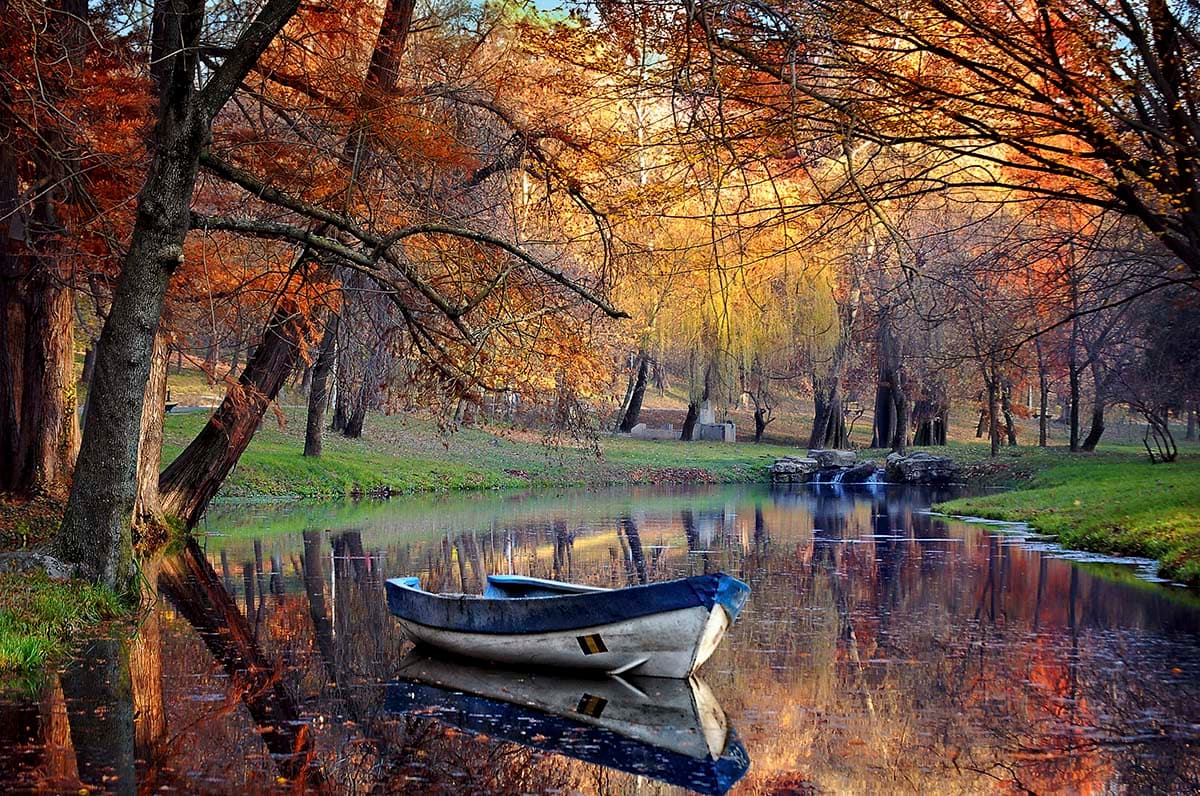 Lone boat drifting across still lake at sunset wallpaper pattern detail