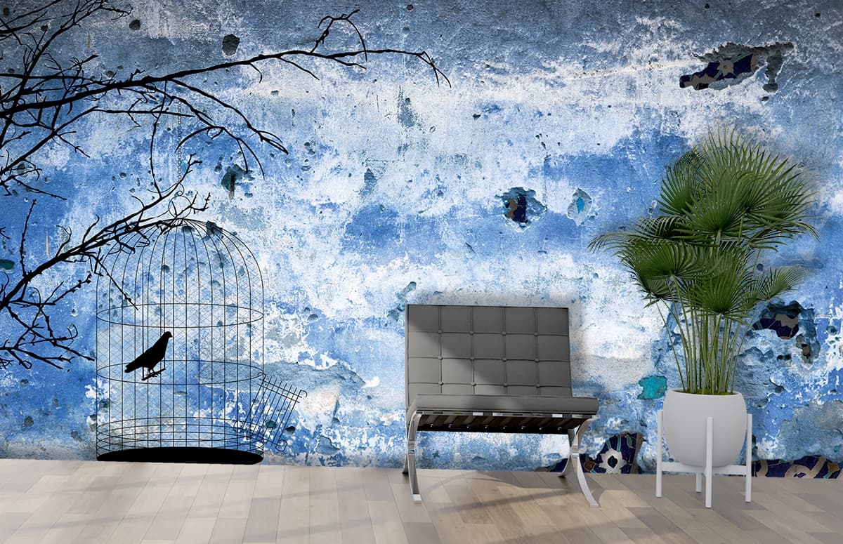 A bird in a cage on a blue wall shown in a room