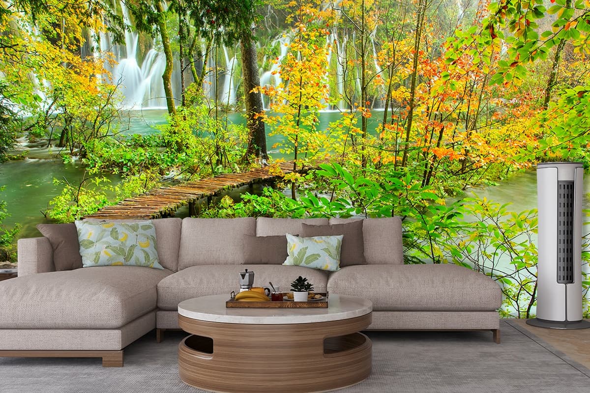 Wooden bridge over water with trees and falls wallpaper shown in a room