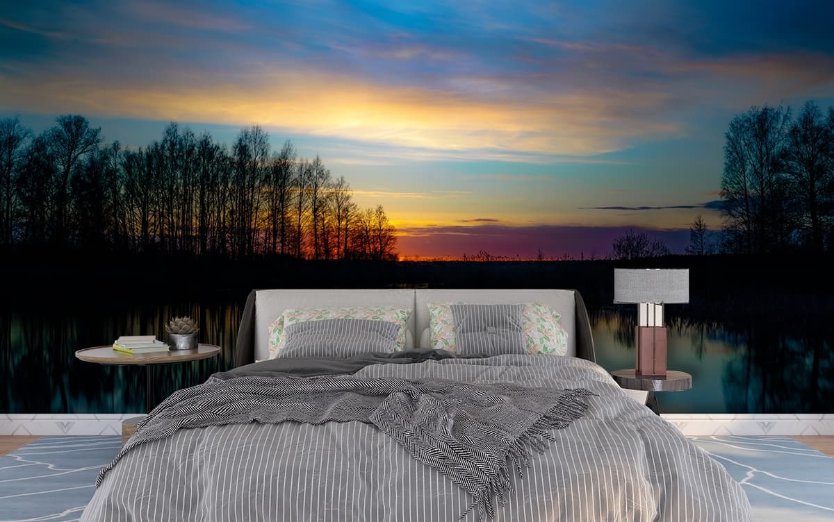Golden sunset over water with trees in calm view wallpaper shown in a room