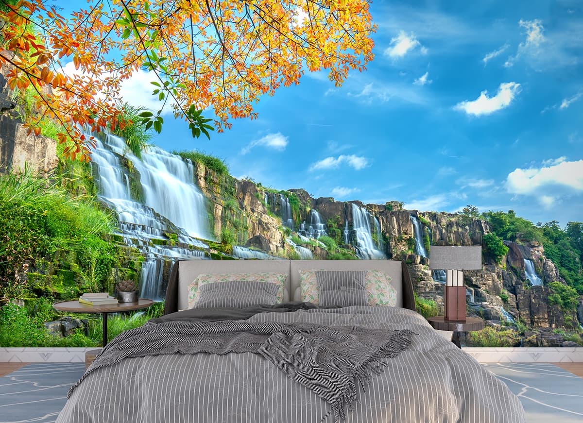 Scenic waterfall with mossy rocks and green trees wallpaper shown in a room