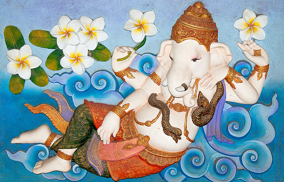 A statue of an elephant lying on a blue surface shown in a room